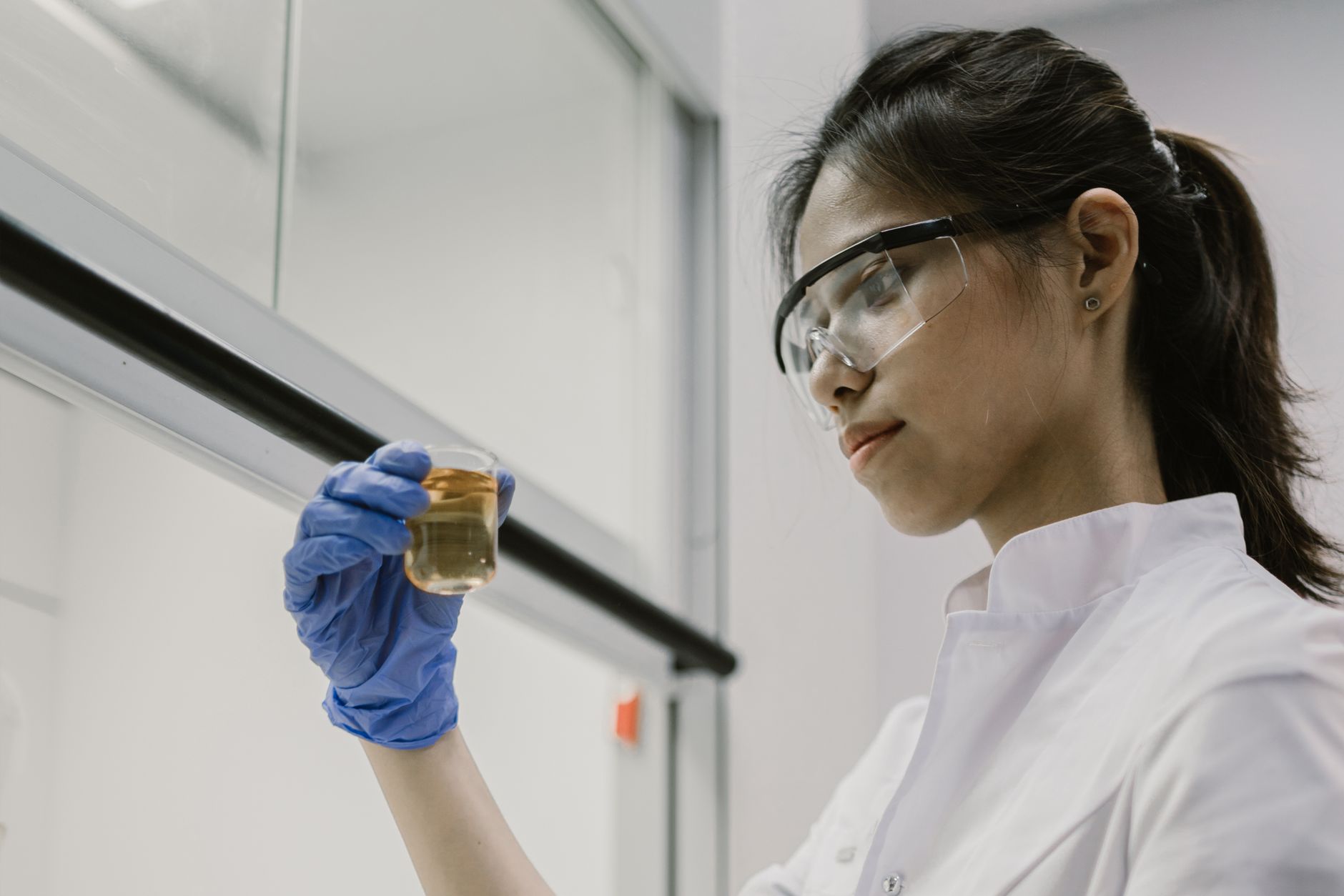 A scientist in protective gear examines a liquid sample in a laboratory